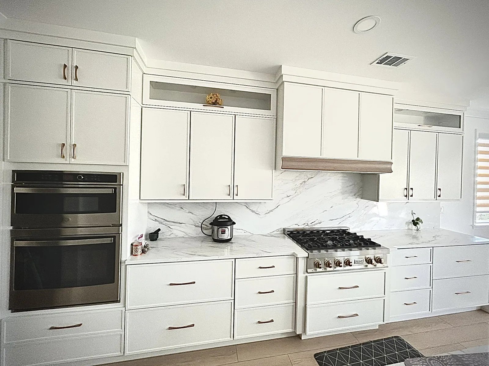 Completed white cabinet kitchen remodel by HQ Construction & Remodeling with built-in appliances, countertops and backsplash